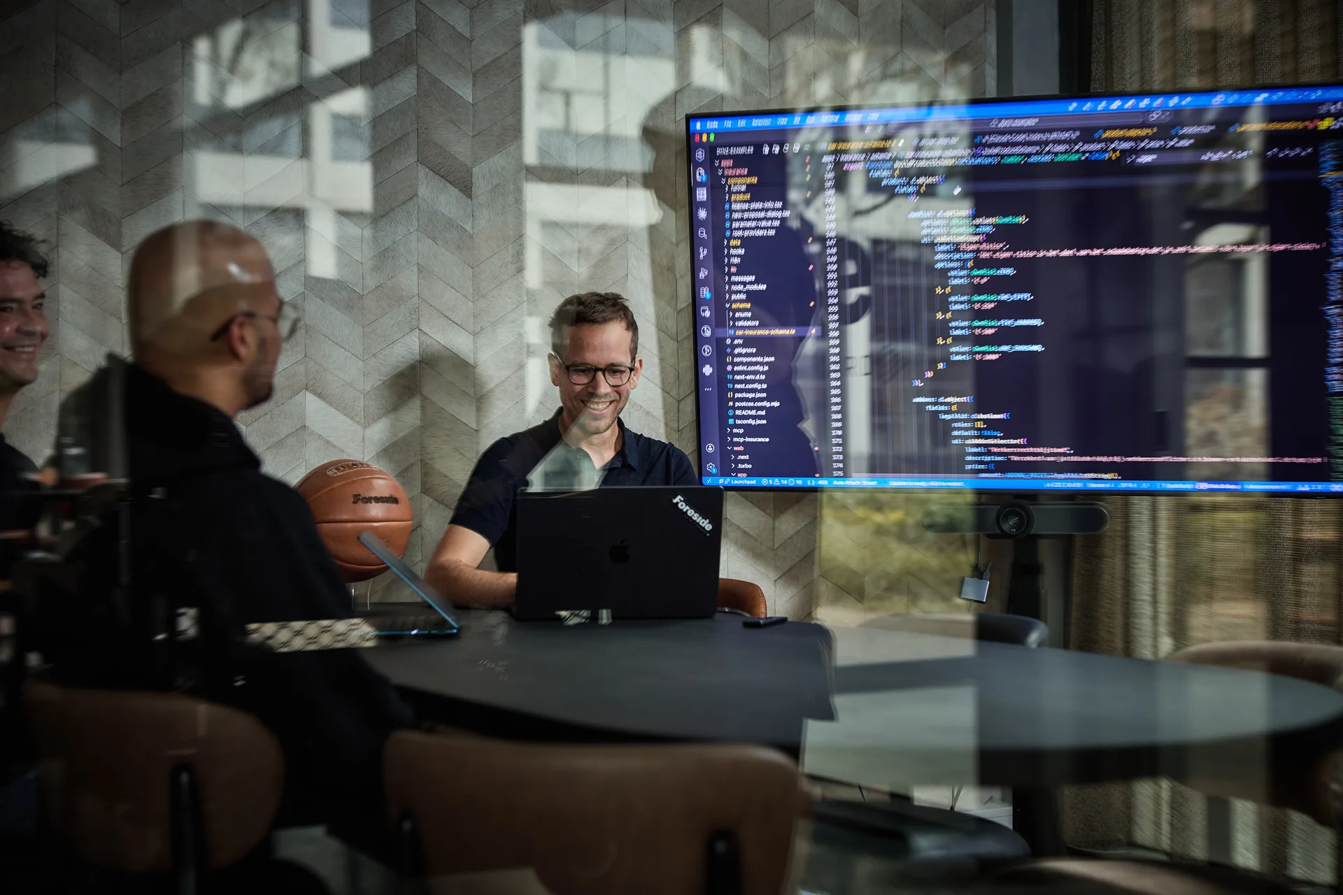 Twee Foreside-engineers kijken samen naar code op een groot scherm